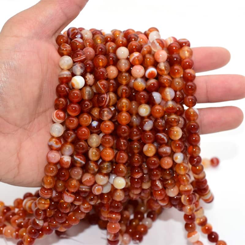 Carnelian Beads held in hand displaying rich red color and polish