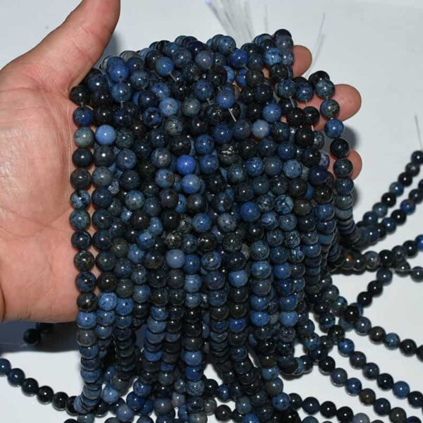 Dumortierite Beads on hand displaying gemstone luster and authentic deep indigo coloration
