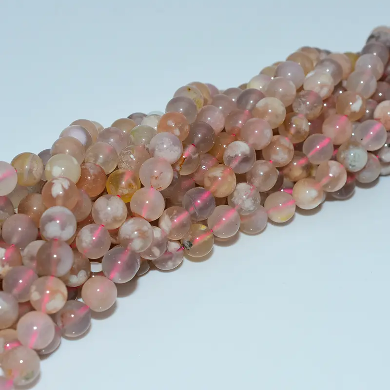 Close-up side view of flower agate beads showing translucent layers and blossom-like inclusions in natural lighting.