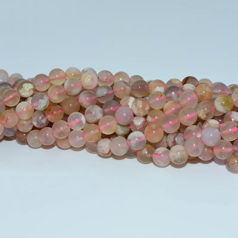 Detailed macro view of flower agate beads highlighting smooth polish, warm pink hue, and unique internal flower patterns.