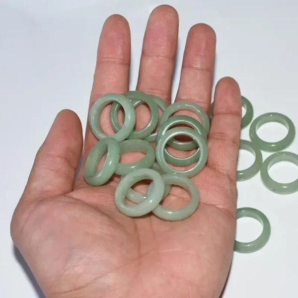 Hand holding multiple Green Aventurine Rings, highlighting polished surface and uniform tone.