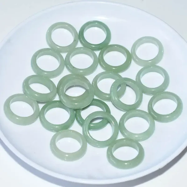 Collection of Green Aventurine Rings arranged on a white plate, emphasizing their round shape and glossy finish.