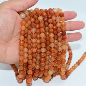 Hand holding Red Aventurine Beads strands to show natural size and luster