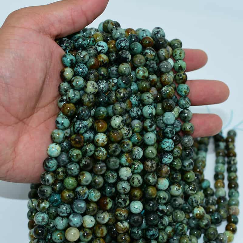 African Turquoise Beads held in hand to show size, luster, and natural tones