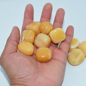 Orange Calcite Tumble stones on hand showing size and shine