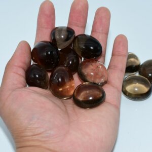 Smoky Quartz Tumbled stones displayed on hand to show size and natural transparency.