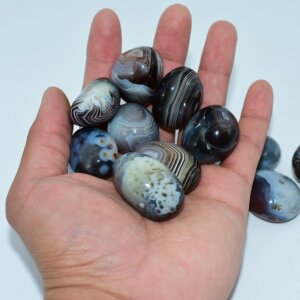 Tumbled Botswana Agate stones shown on hand to display size and polish quality