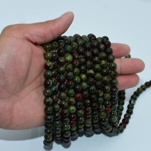 Dragon Blood Jasper Beads on hand display for bulk bracelet strand selection